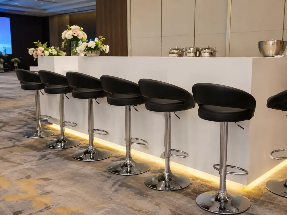 Adjustable black cushioned bar stools arranged along a white bar counter