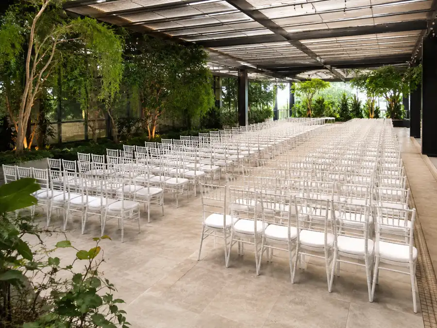White Chiavari chairs arranged in rows under a covered garden terrace