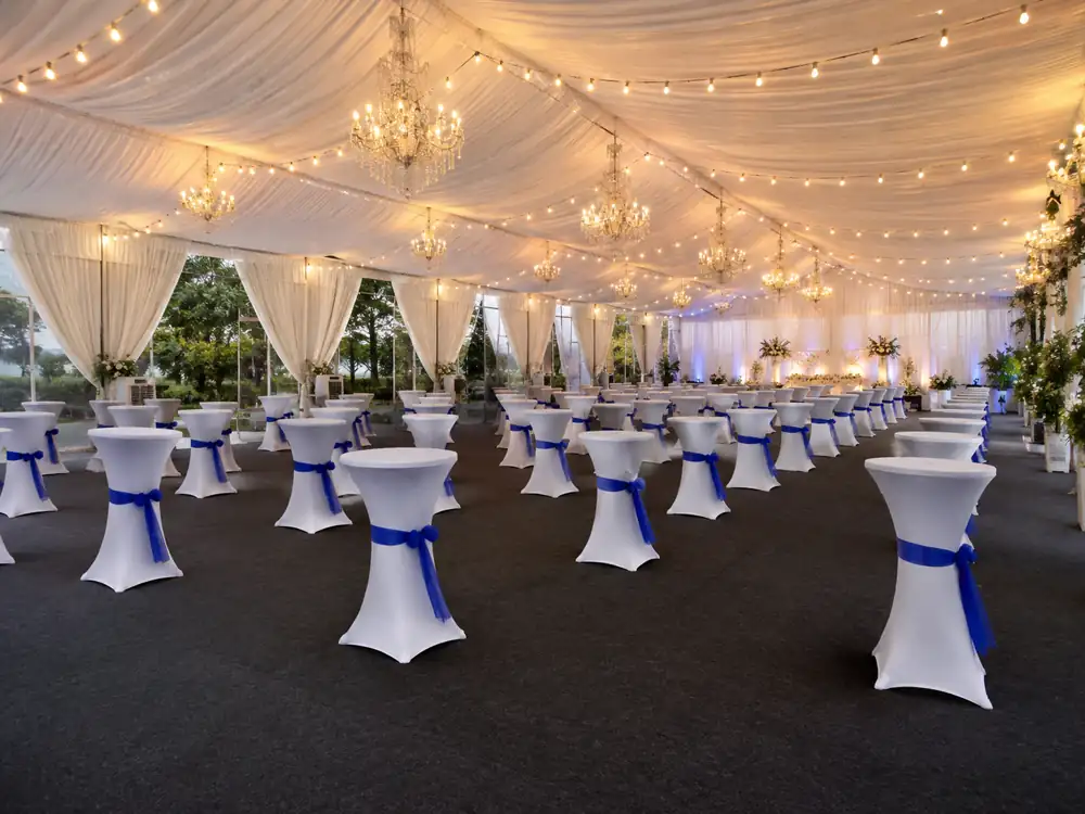 White cocktail tables with blue sash under a decorated canopy
