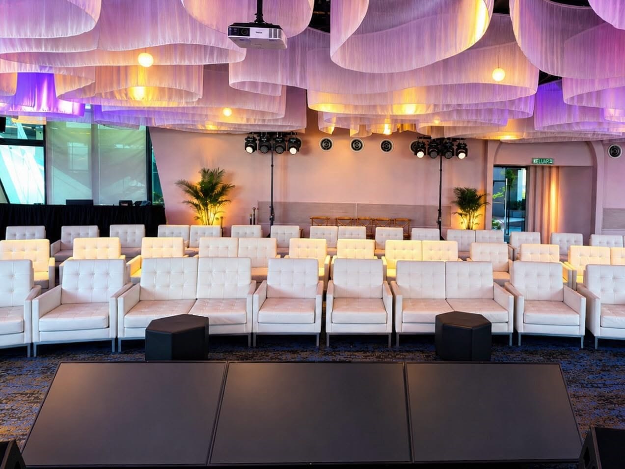 Rows of white lounge chairs arranged as VIP seating facing a stage