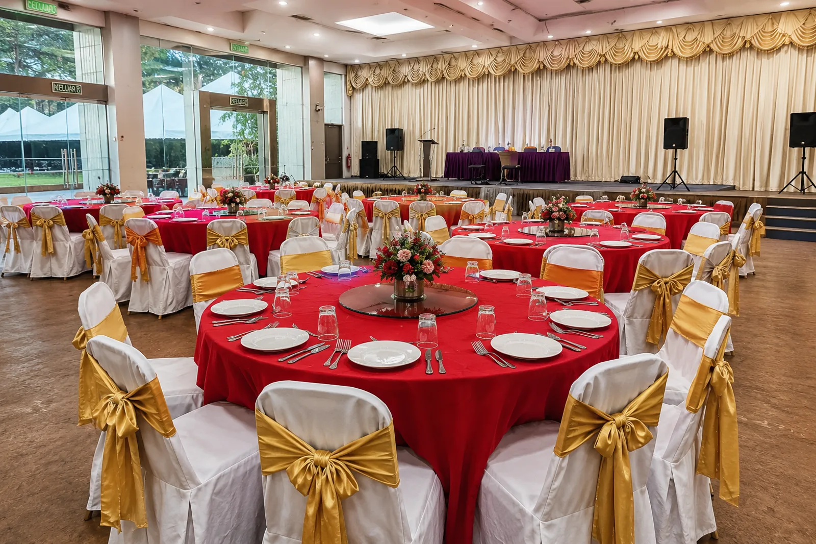 Red round table cloth setup with covered banquet chairs and gold chair sash